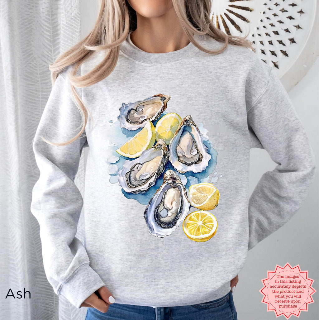 Ash-colored Oyster Shell sweatshirt featuring watercolor oysters and lemon accents, Gildan 18000 DTG pullover, cozy coastal aesthetic pullover for ocean and beach lovers.