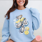 Coraline Blue Oyster Shell sweatshirt with watercolor oysters and lemon slices, Gildan 18000 DTG pullover, coastal aesthetic and beachy marine life fashion.