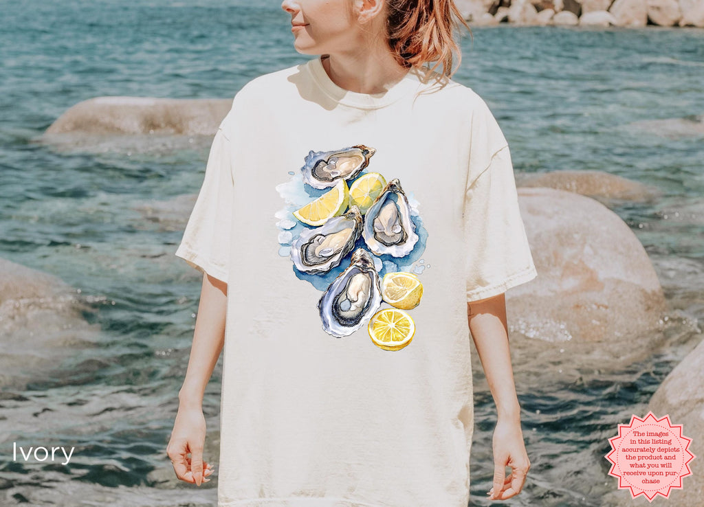 Ivory Comfort Colors T-shirt featuring detailed watercolor oysters and lemon slices, perfect for coastal fashion and summer outfits.
