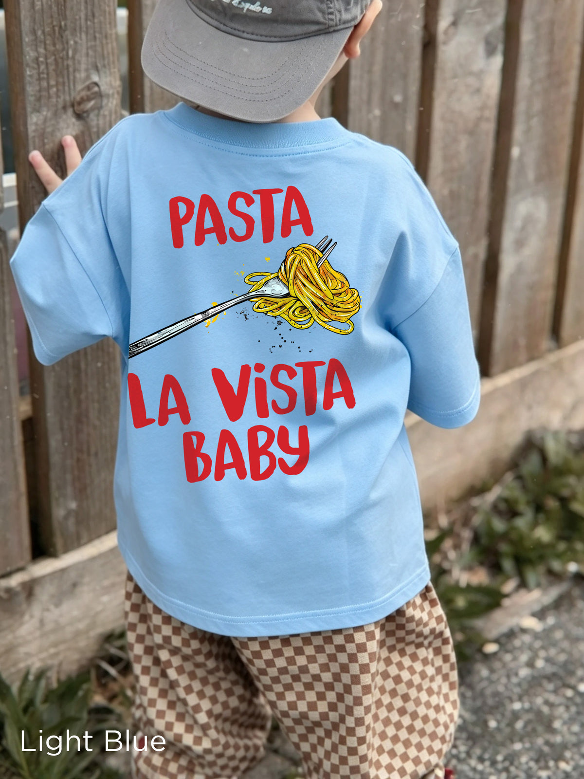 Child modelling the Pasta La Vista Baby kids' T-shirt, showcasing the colourful spaghetti graphic on the back.