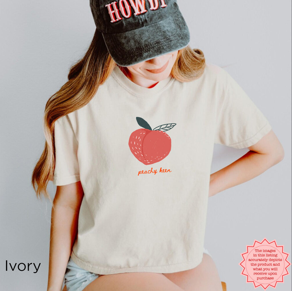 Peachy Keen Crop Shirt in Ivory with a vibrant peach graphic, ideal for a laid-back yet trendy summer aesthetic.