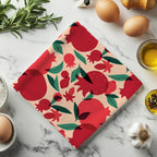 That’s Amore pomegranate tea towel with colorful painted fruit design styled on marble countertop with olive oil and herbs