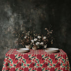 Rustic dining table styled with a bold pomegranate tablecloth in a dramatic Mediterranean interior