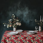 Italian-inspired pomegranate tablecloth on a dining table with neutral plates and floral centerpiece against a textured dark wall