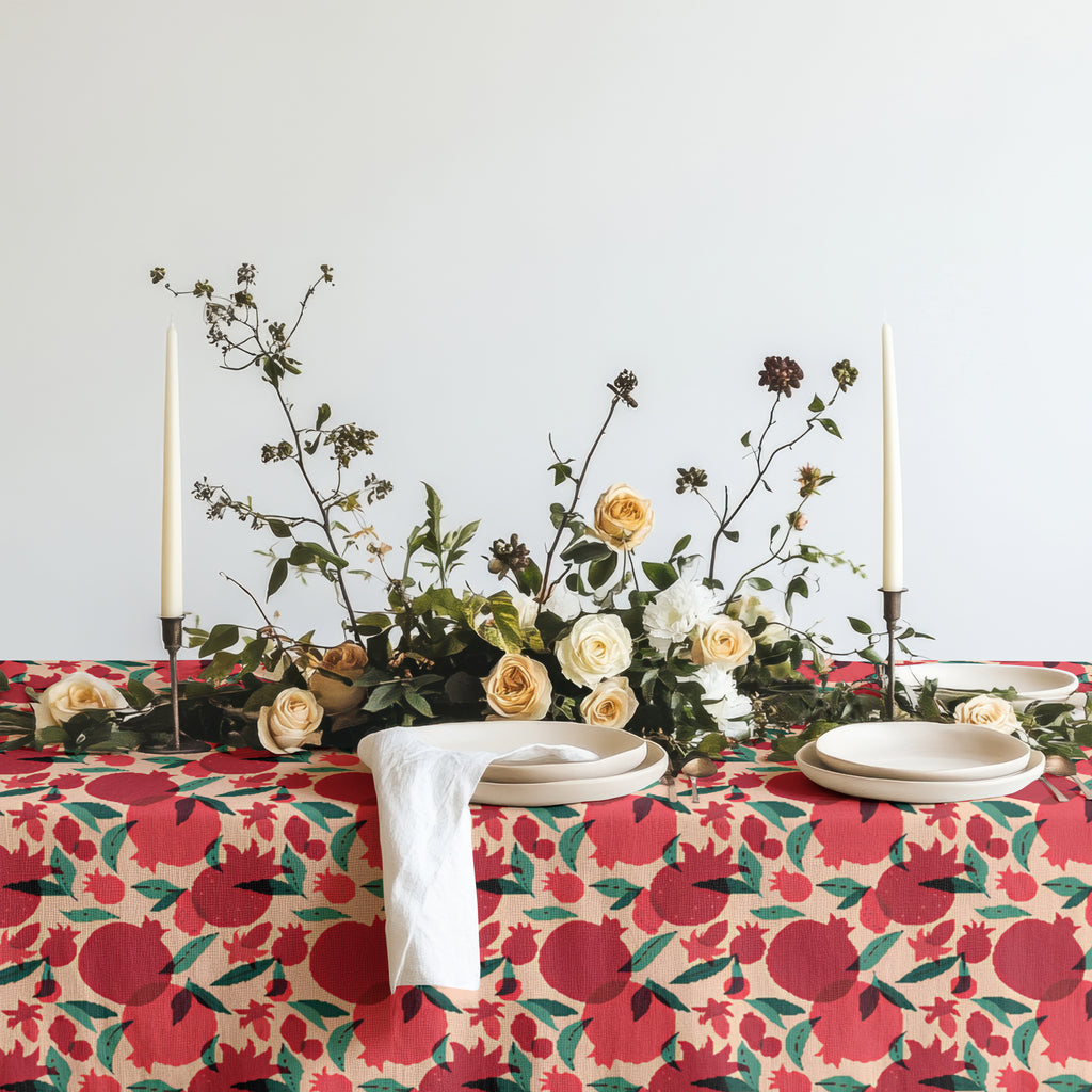 Close-up of pomegranate tablecloth fabric with ceramic plates and woven placemats on a dining table