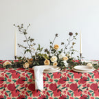 Close-up of pomegranate tablecloth fabric with ceramic plates and woven placemats on a dining table
