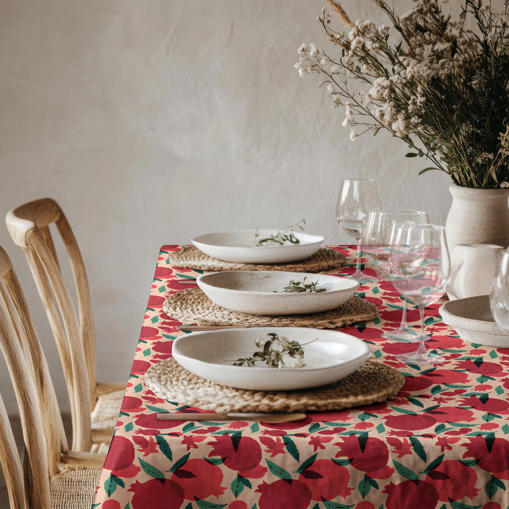 Mediterranean pomegranate tablecloth draped over dining table with wooden chairs in a bright minimalist room