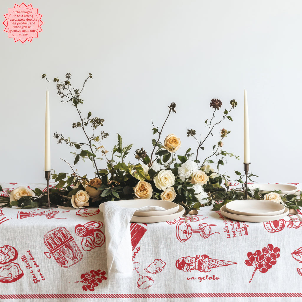 Italian food-themed red tablecloth with hand-drawn illustrations of pasta, ice cream, and pizza, placed on a table with a floral arrangement, plates, and candles.