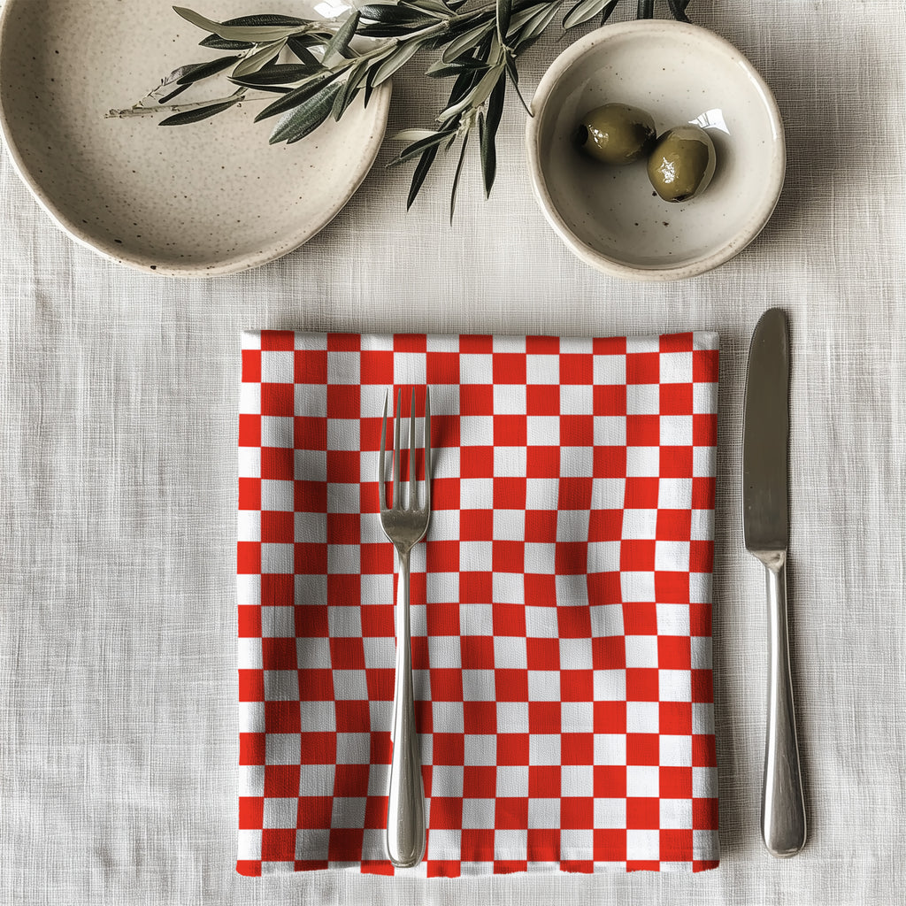 Single red checker dinner napkin folded on table showcasing one-sided gingham print and reusable cotton fabric