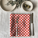 Single red checker dinner napkin folded on table showcasing one-sided gingham print and reusable cotton fabric