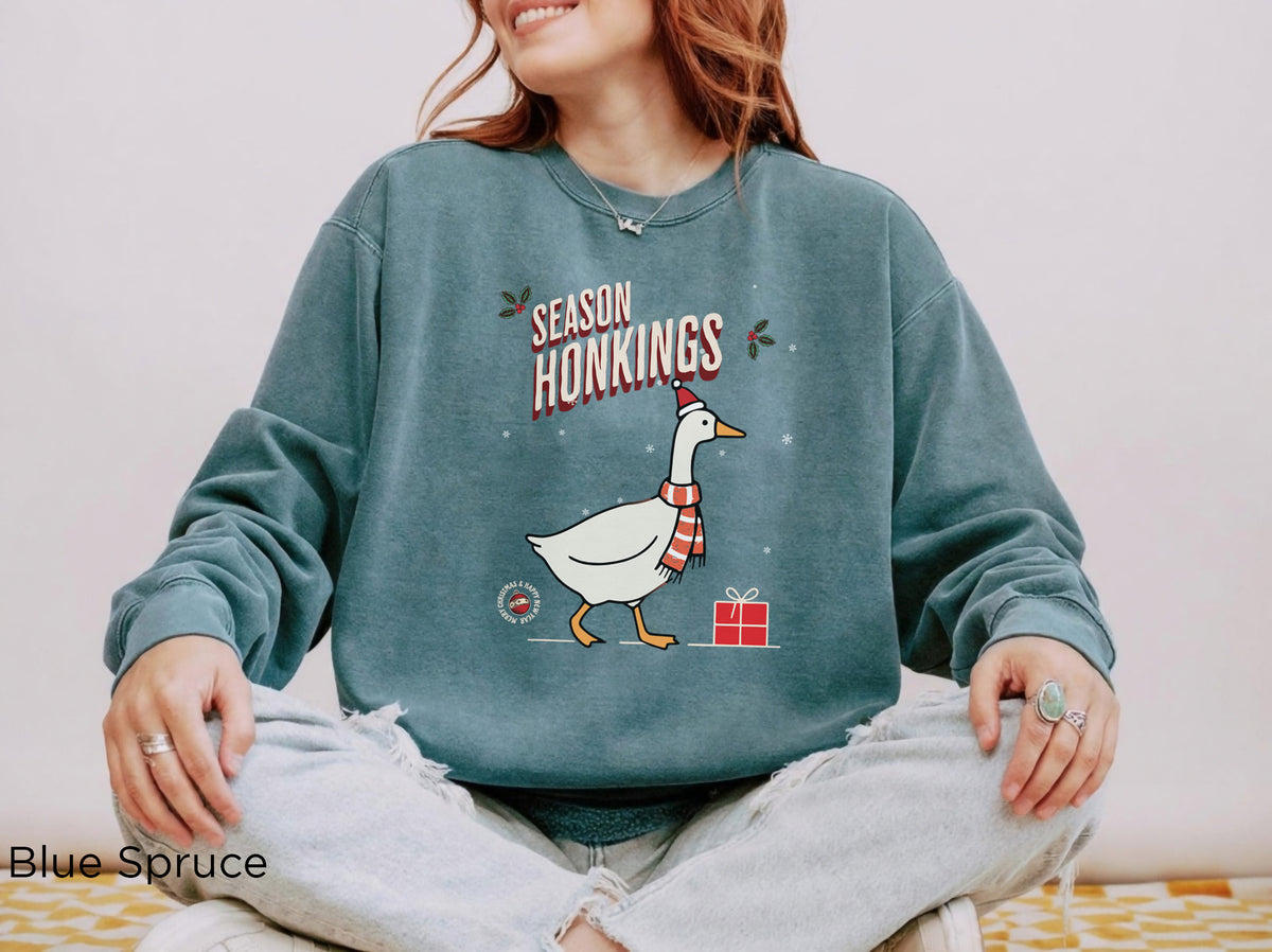 Blue Spruce festive crewneck with illustrated Christmas goose, Santa hat, red scarf, snowflakes and gift design.