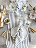 Slate blue hand drawn stripes table runner styled on a modern dining table with white dinnerware and glassware
