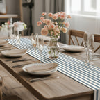 Modern dining table featuring a slate blue striped table runner with elegant white plates and wine glasses