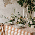 Terracotta and ivory striped tablecloth creating a warm Mediterranean-inspired tablescape with elegant dinnerware and candlelight.
