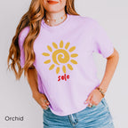 Lifestyle image: Woman wearing the SOLE T-shirt during a relaxed outdoor moment, highlighting the minimalist golden sun graphic and casual boxy fit.