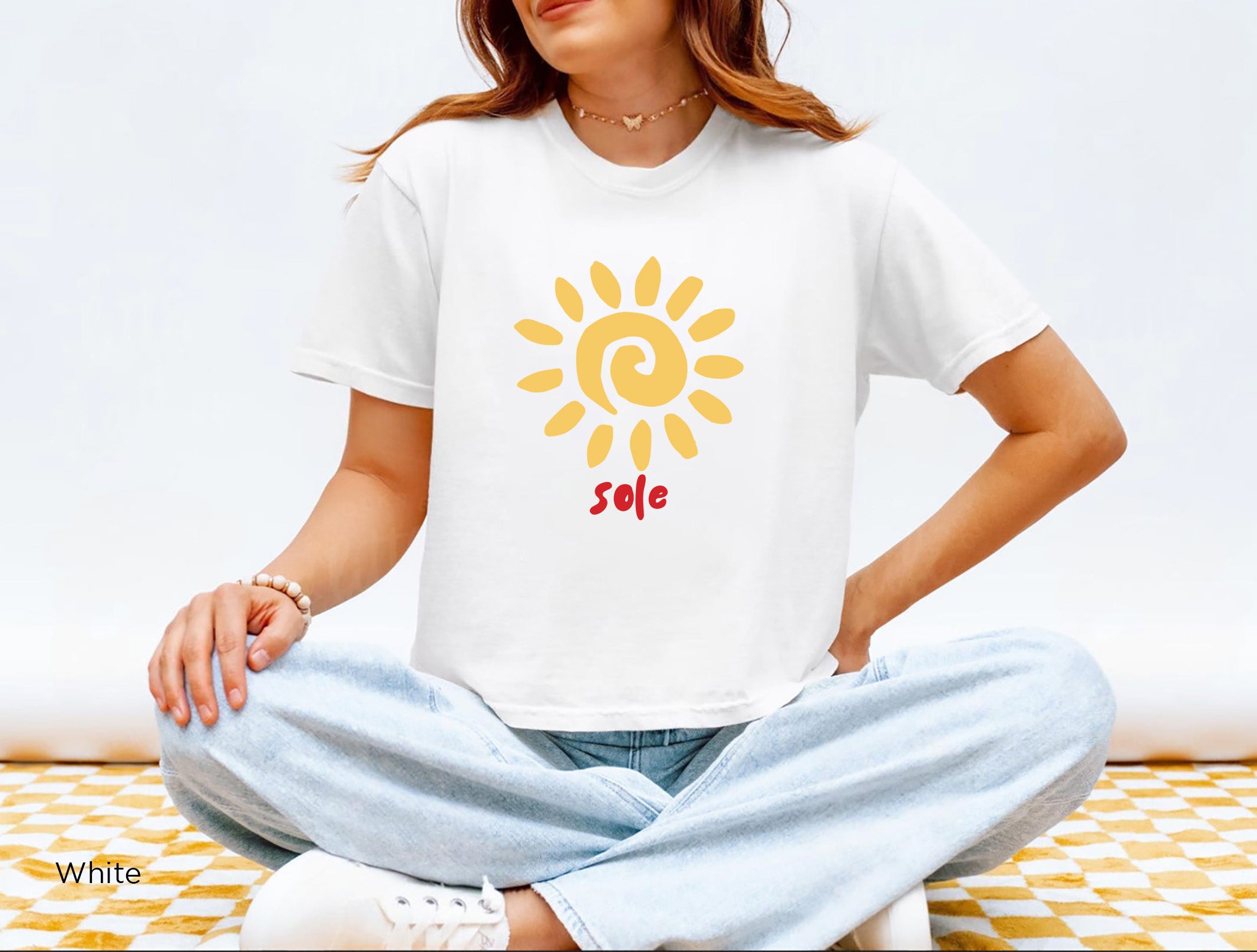 Casual holiday look: Woman wearing the SOLE graphic T-shirt with shorts and sandals in a bright outdoor setting, evoking a sunny Mediterranean holiday.