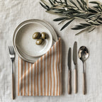 Terracotta Stripes Table Napkin styled on an elegant dining table with neutral tableware and natural accessories.