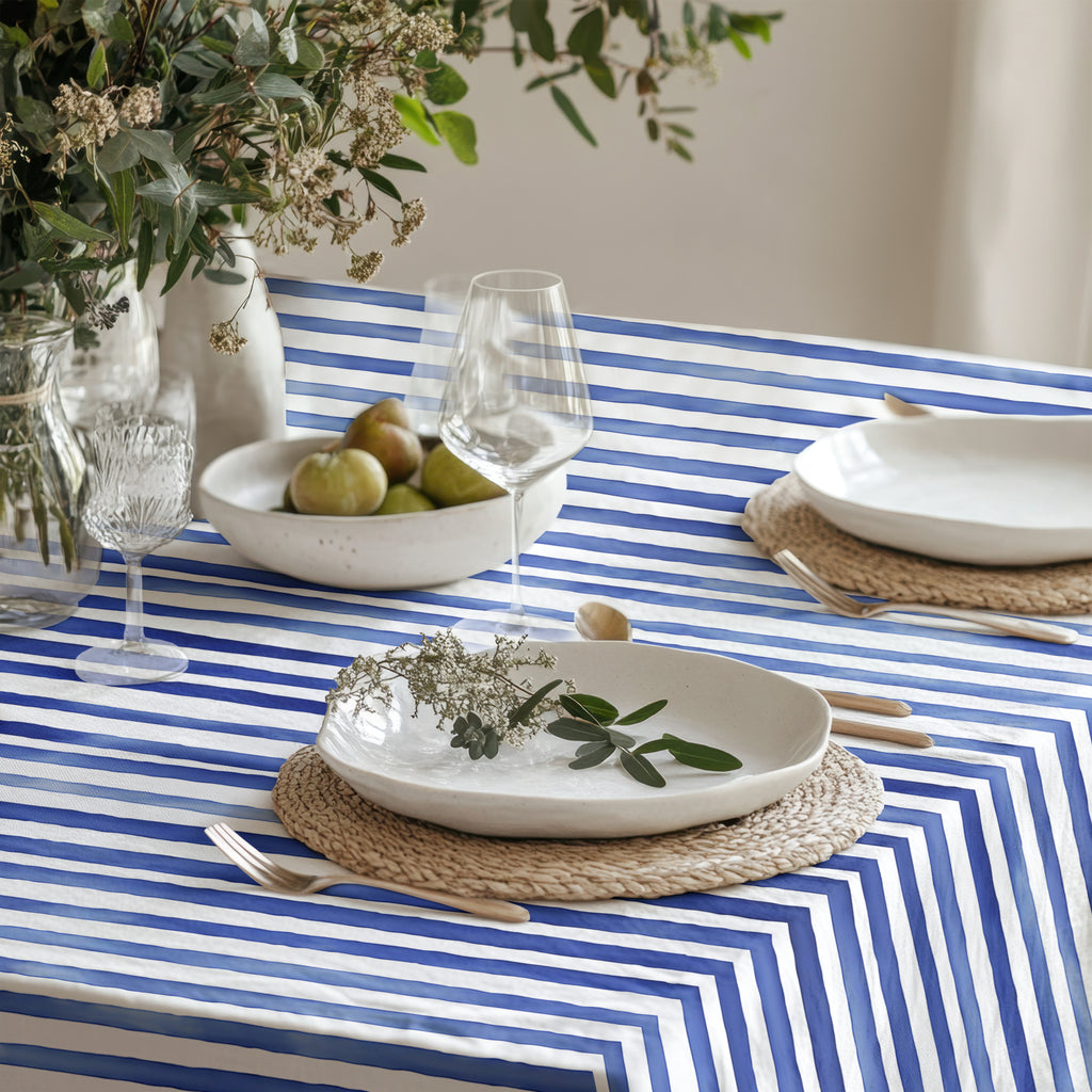 Full view of a beautiful dining table with the Watercolor Blue Stripes Tablecloth (58"x58") featuring fresh flowers and simple, elegant dinnerware.