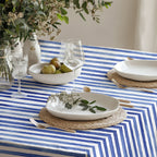 Full view of a beautiful dining table with the Watercolor Blue Stripes Tablecloth (58"x58") featuring fresh flowers and simple, elegant dinnerware.