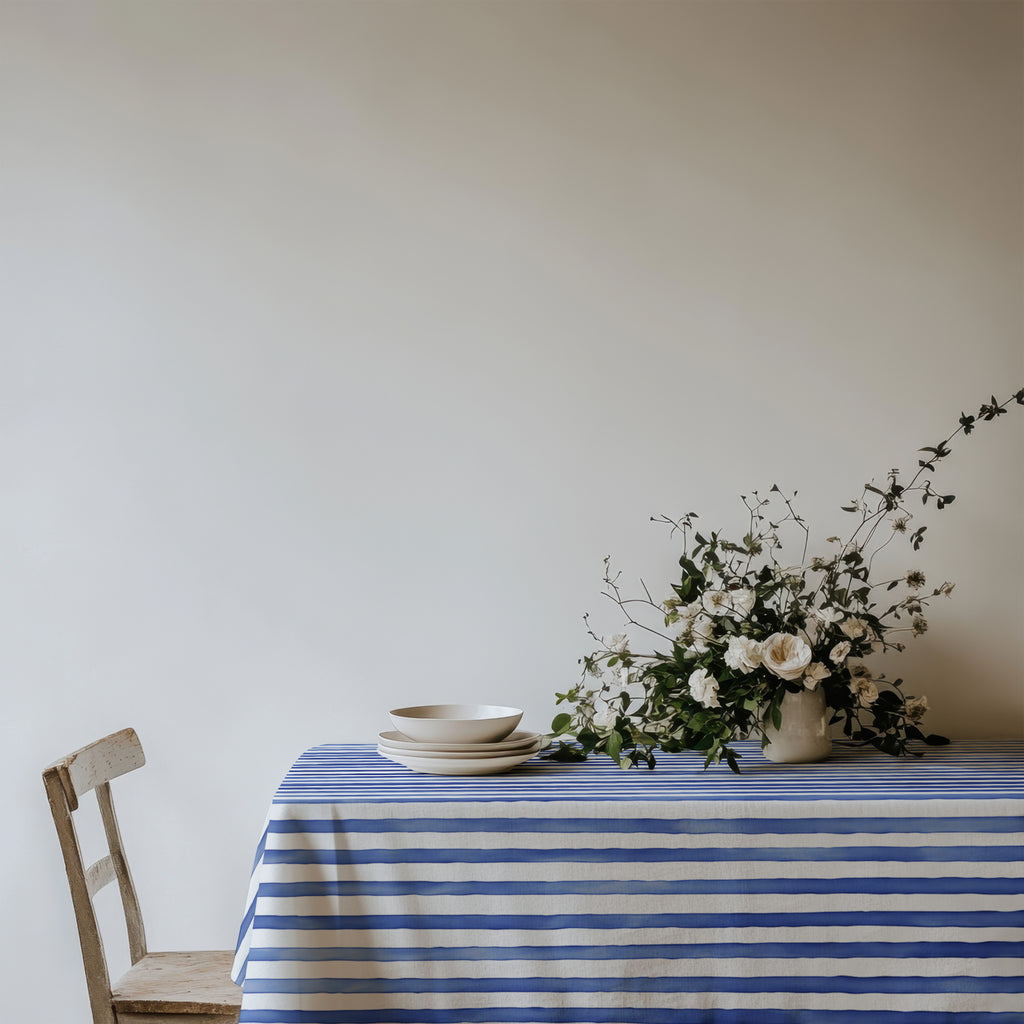 Coastal style dining area with a Watercolor Blue Stripes Tablecloth in cotton twill fabric (58"x102"), offering a sophisticated and fresh look for gatherings.